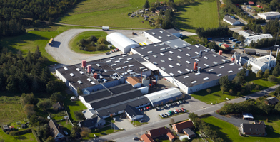 Luchtfoto van het hoofdkantoor van het bedrijf, met een groot modern complex omgeven door groen.